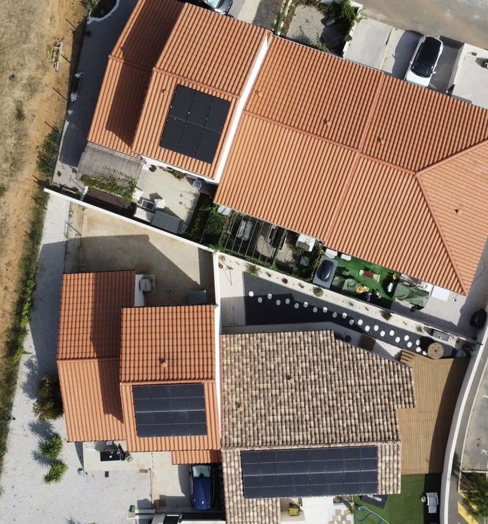 Photo aérienne d’un système de panneaux solaires pour l’autoconsommation énergétique pour trois maisons